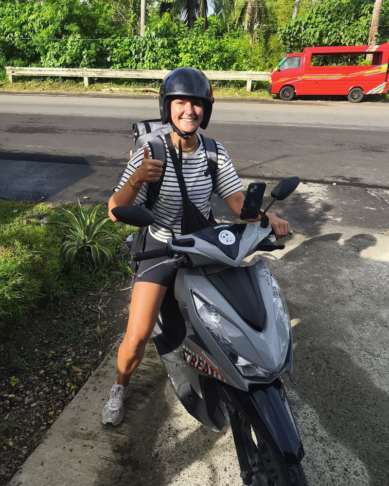 Smiling rider in a helmet giving a thumbs-up on a grey Honda BeAT