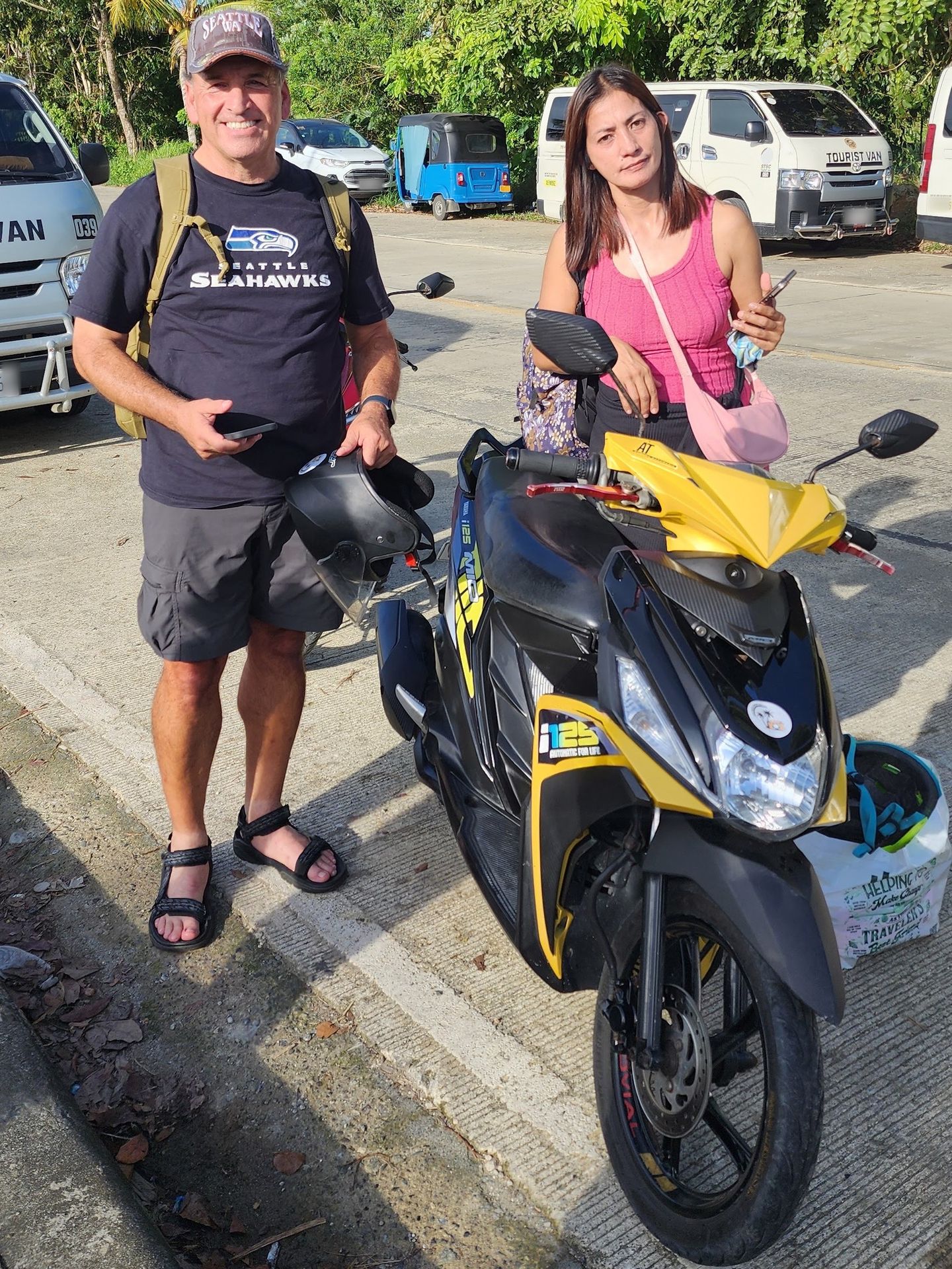 Yellow and black Yamaha Mio i 125 scooter with two smiling travellers